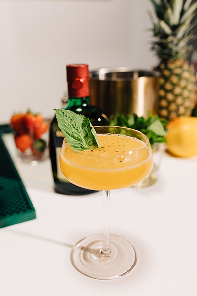 The Buchanan's peppered pineapple drink in a martini glass and garnished with a basil leaf
