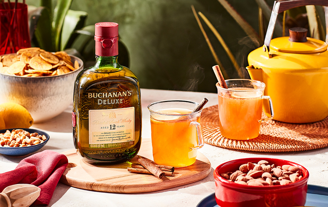 Two Buchanelazo cocktails sitting on a table next to a Buchanan's Deluxe bottle